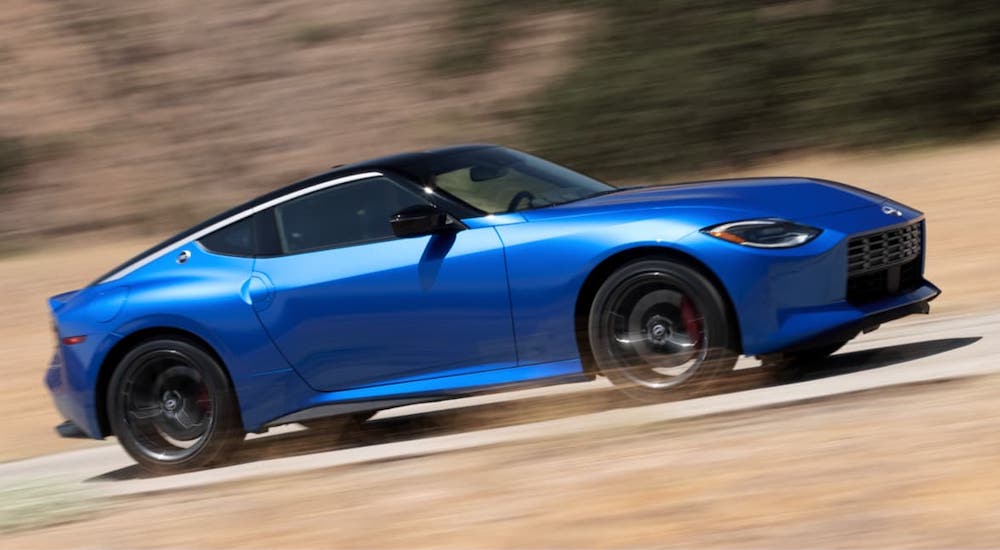A blue 2023 Nissan Z is shown from the side driving at speed.