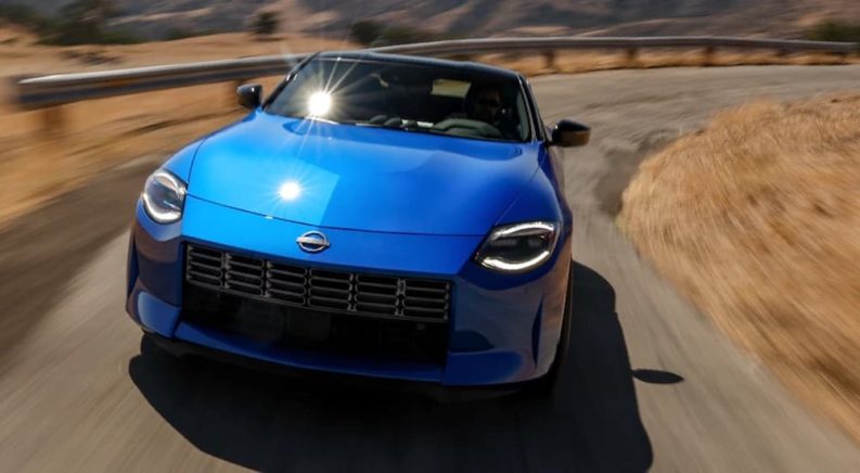 A blue 2023 Nissan Z is shown from the front white rounding a corner after leaving a Nissan dealer.