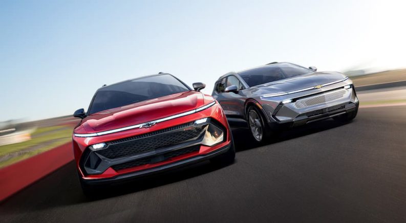 A red 2024 Chevy Equinox RS EV and a silver Equinox EV are shown from the front driving down the road after leaving a California Chevrolet dealer.