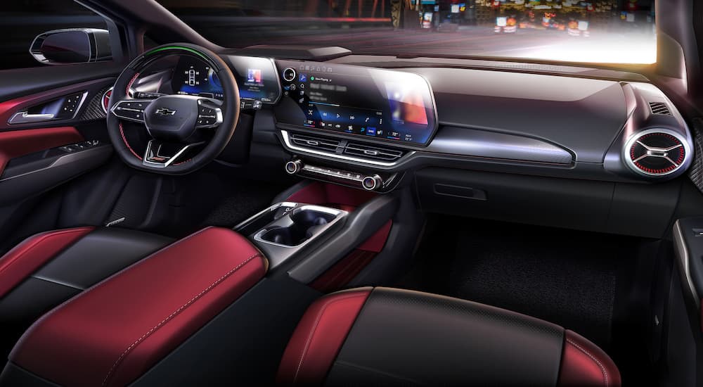 The red and black interior of a 2024 Chevrolet Equinox EV is shown from the passenger seat.