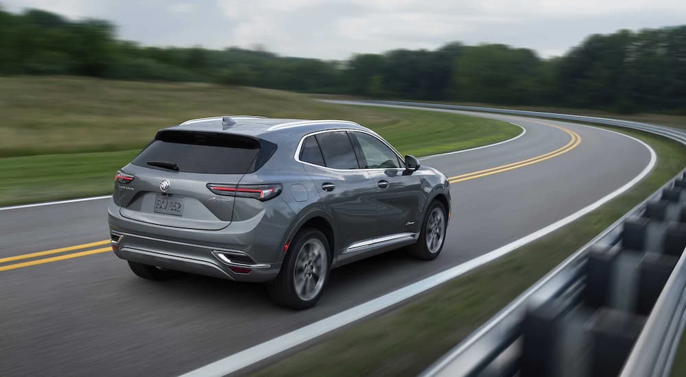 A grey 2022 Buick Envision Avenir is shown rounding a corner on an empty road.