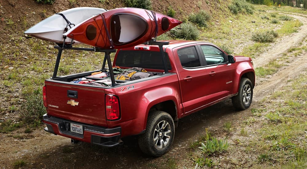A red 2020 Chevy Colorado is shown driving to a campsite after visiting a Certified Pre-Owned Chevrolet dealer.