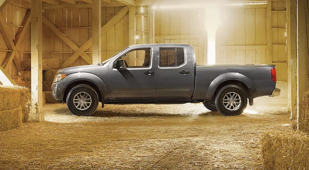A silver 2021 Nissan Frontier is shown from the side parked in a barn.