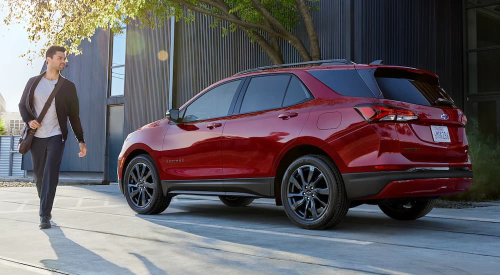 A red 2022 Chevy Equinox RS is shown next to a person in a parking lot after leaving a Chevy dealer near you.