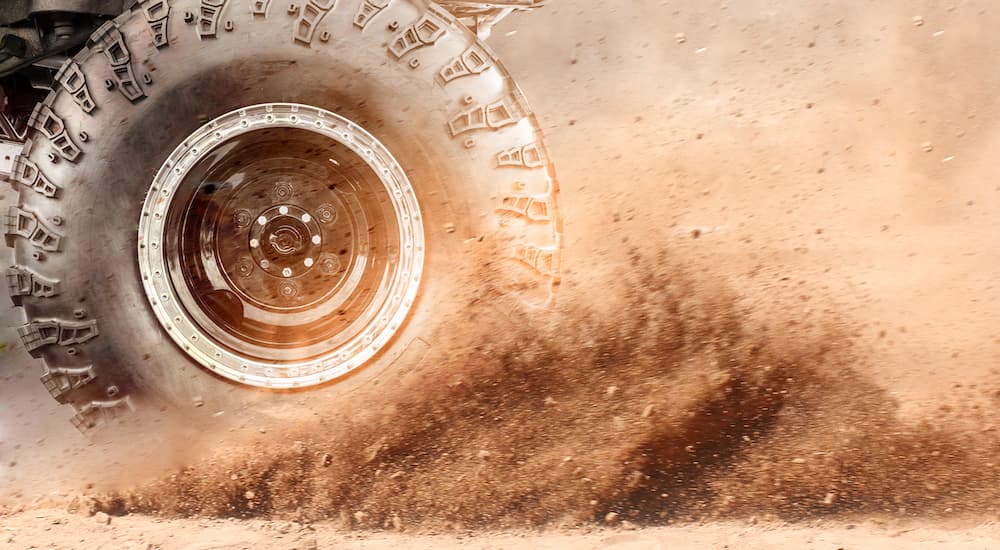 An off-road tire is shown spinning in dirt.