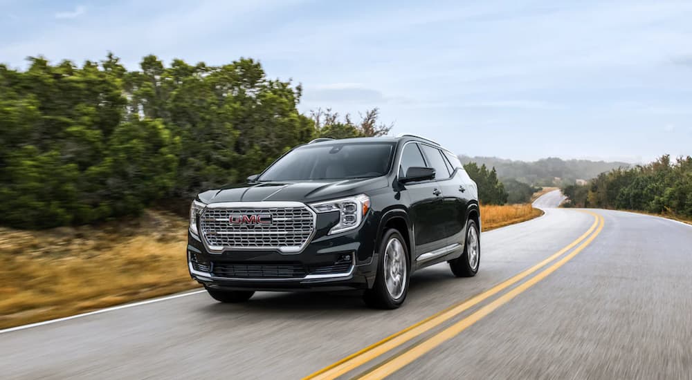 A black 2022 GMC Terrain Denali is shown from the side driving on an open road.