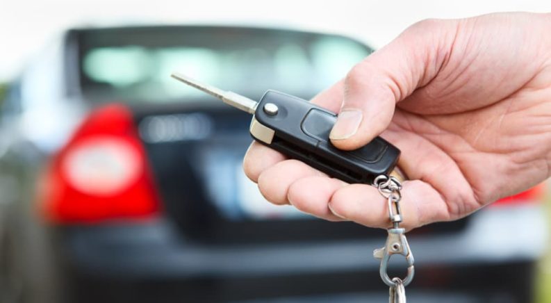 A person is shown holding a car key after searching for online car sales.