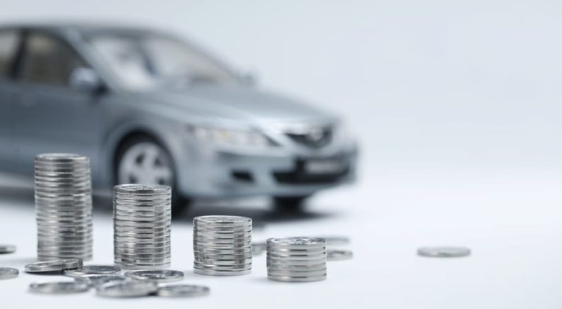 A silver toy car is shown behind coins after someone searched 'how to sell my car.'