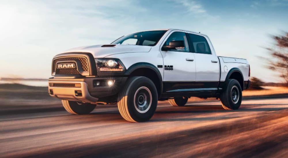 A white 2018 Ram 1500 is shown driving on an open road.