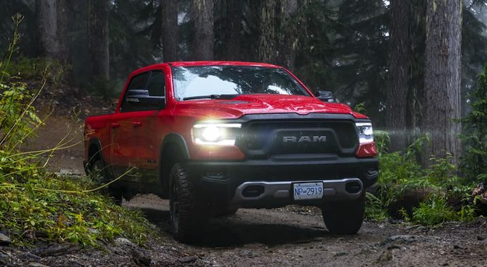 A red 2019 Ram 1500 Rebel is shown driving on a forest trail.