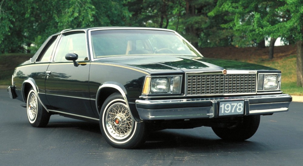 A black 1983 Chevy Malibu Classic is shown parked in an empty lot.