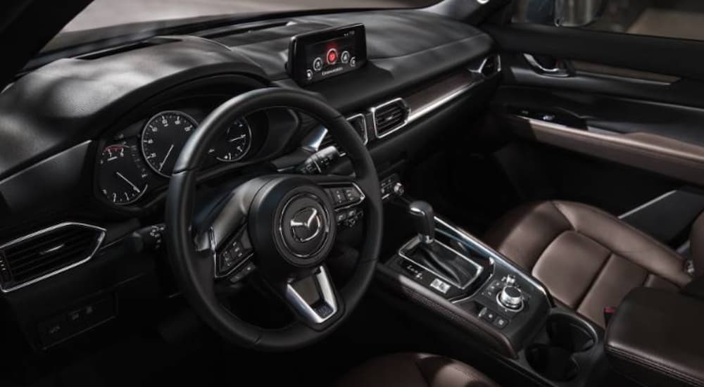 The black interior of a 2022 Mazda CX-5 is shown from the drivers door opening.
