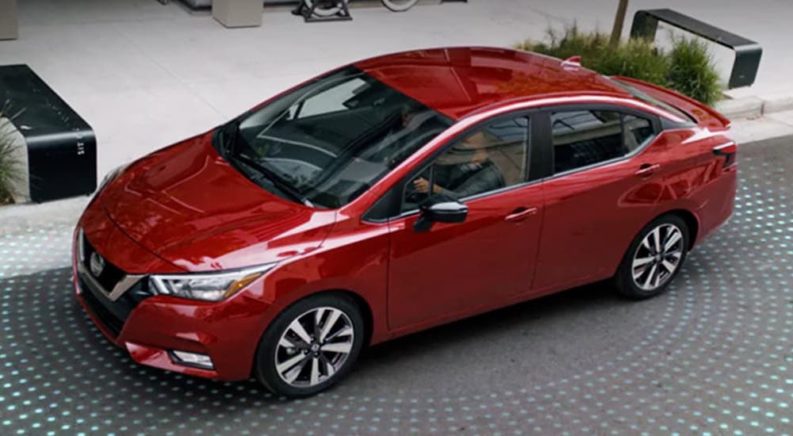 A red 2021 Nissan Versa is shown from above at an angle while it parks with simulated sensor range displayed around it.