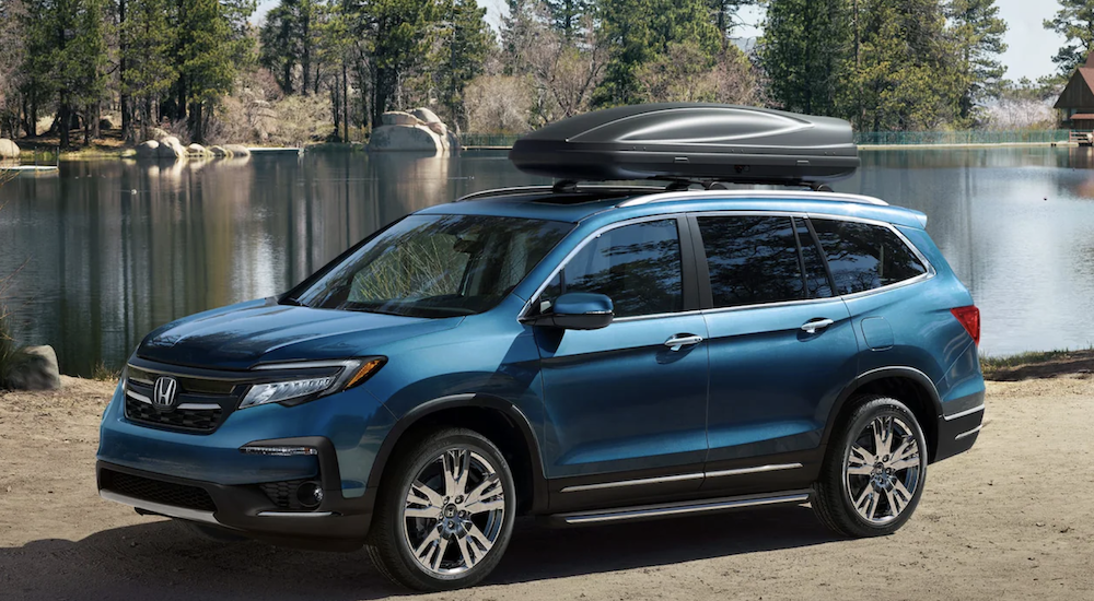 A blue 2022 Honda Pilot Elite is shown from the side parked in front of a body of water.