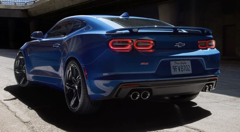 A blue 2022 Chevy Camaro is shown from the rear parked during a 2022 Chevy Camaro vs 2022 Ford Mustang comparison.