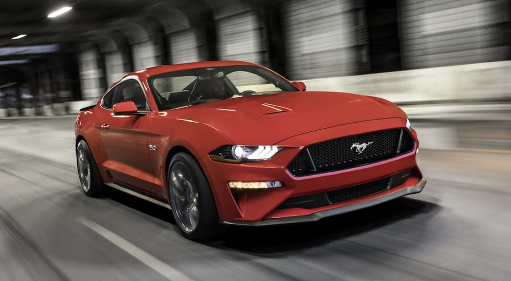 A red 2022 Ford Mustang is shown from the front driving through a tunnel.