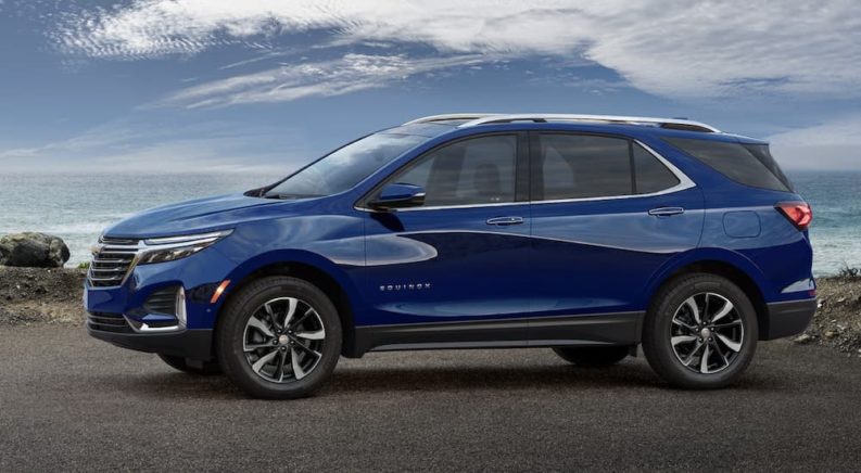 A blue 2022 Chevy Equinox is shown from the side parked in front of a body of water.