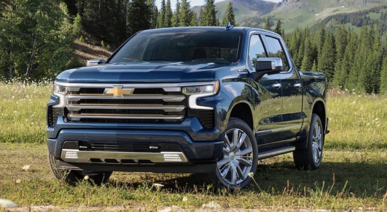 A blue 2022 Chevy Silverado 1500 High Country is shown from the front parked in a grass field.