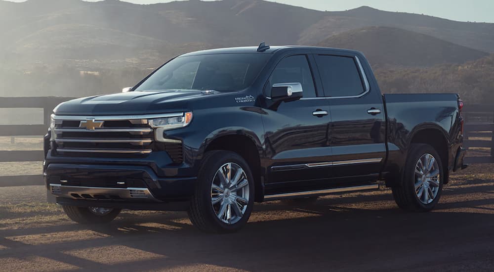 A blue 2022 Chevy Silverado 1500 is shown from the side parked next to a fence during a 2022 Chevy Silverado 1500 vs 2022 Ford F-150 comparison.