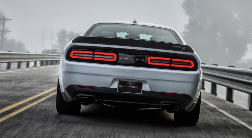 A white 2022 Dodge Challenger Hellcat is shown from the rear driving on an open road.
