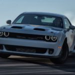 A white 2022 Dodge Challenger Hellcat is shown from the front doing a burn out.