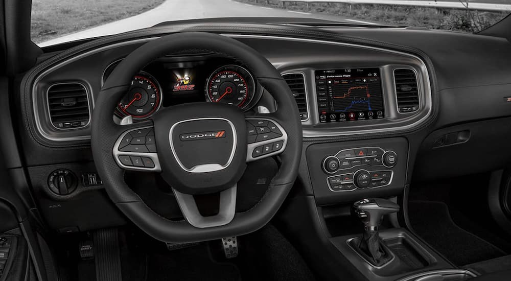 The black interior of a 2022 Dodge Charger shows the steering wheel and information screen.