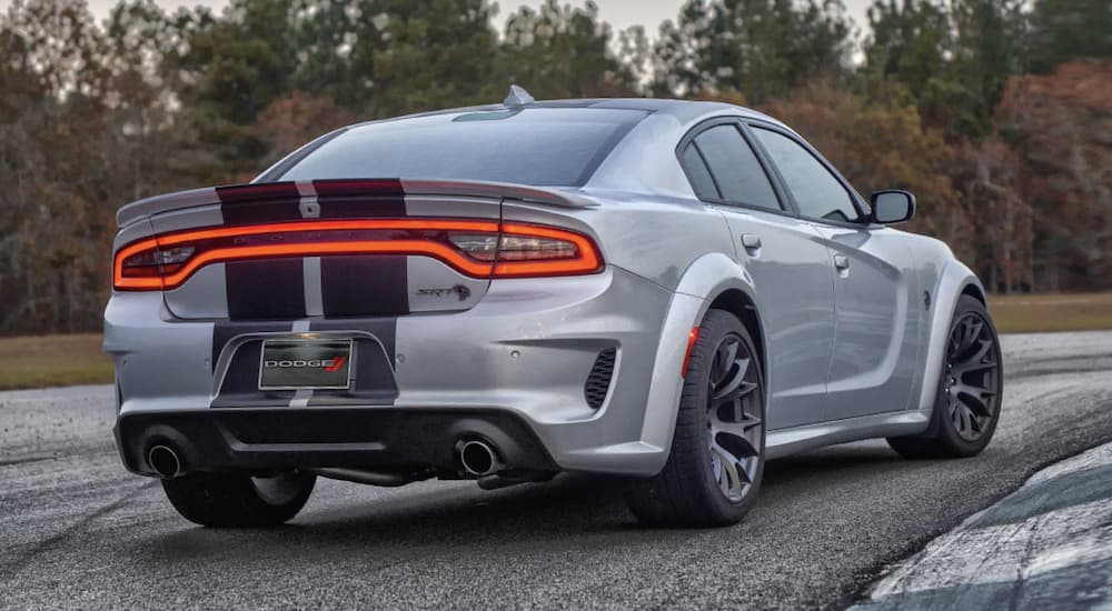 A silver 2022 Dodge Charger is shown from the rear driving on a track.