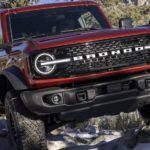 A red 2022 Ford Bronco is shown from the front off-roading in the mountains.