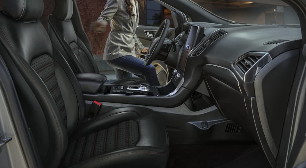 The black interior of a 2022 Ford Edge ST shows the front seats and steering wheel.