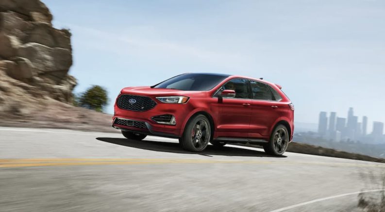 A red 2022 Ford Edge ST is shown from the side driving on an open road.