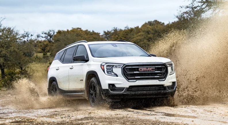 A white 2022 GMC Terrain AT4 is shown from the front off-roading through a mud puddle.