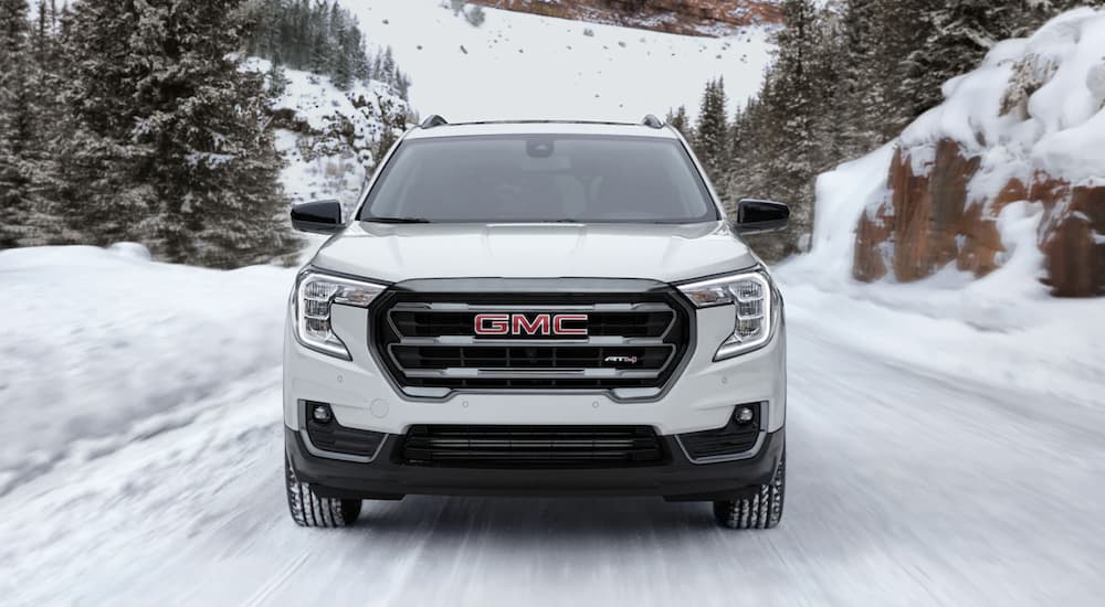 A white 2022 GMC Terrain AT4 is shown from the front driving on a snow covered road.