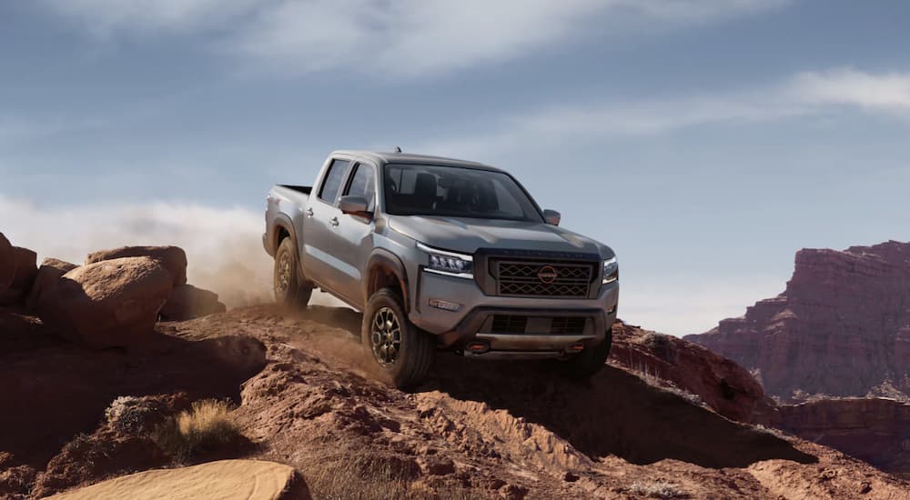 A grey 2022 Nissan Frontier is shown off-roading in the mountains.