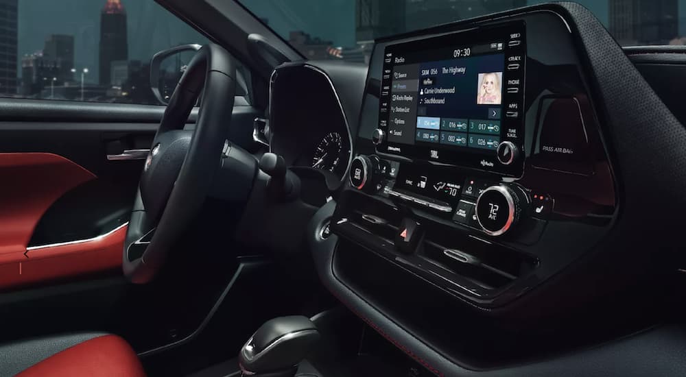 The black interior of a 2022 Toyota Highlander XSE shows the steering wheel and infotainment screen.