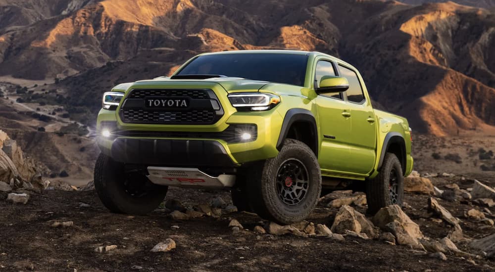 A lime green 2022 Toyota Tacoma TRD is shown off-roading in the mountains.