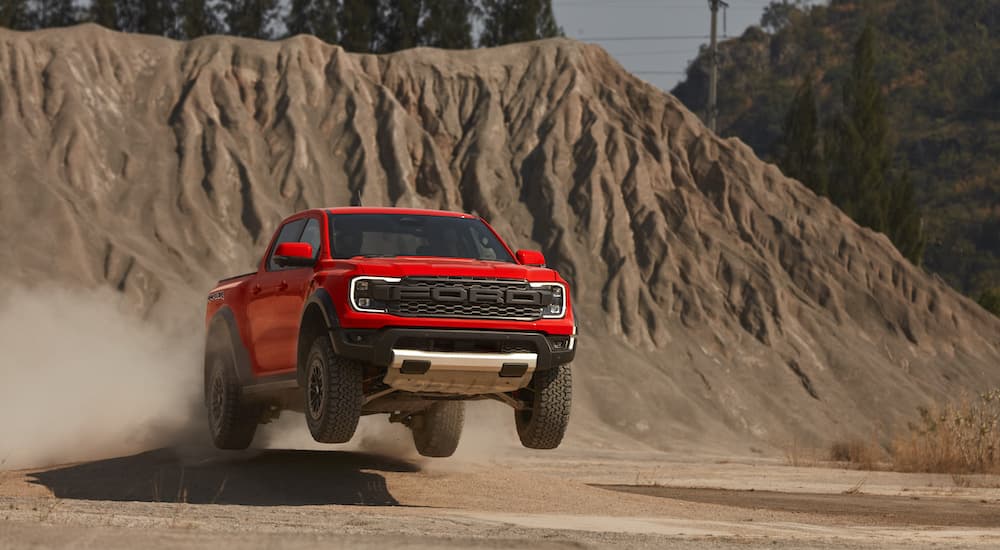A red 2023 Ford Ranger Raptor is shown from the front as it performs a jump.