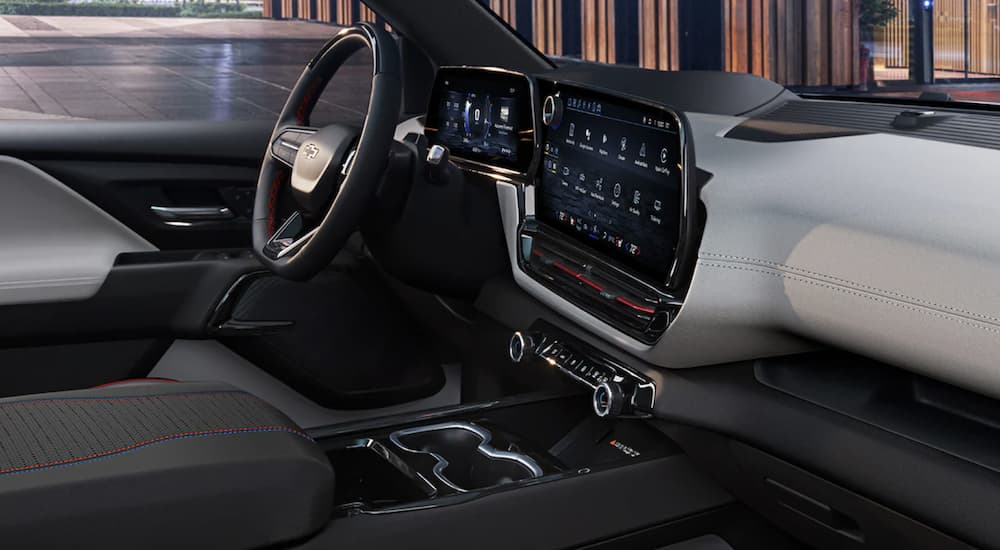 The black interior of a 2024 Chevy Silverado EV shows the steering wheel and infotainment screen.