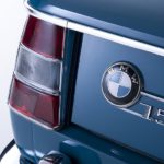 A close up shows the badging on a blue 1965 BMW 1500 Neue Klasse.