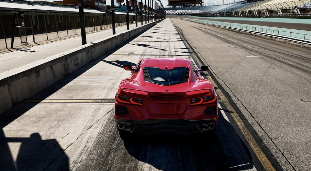A red 2022 Chevy Corvette is shown from the rear parked on a racetrack.