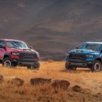 A red and a blue 2022 Ram 1500 TRX are shown facing each other in a field.