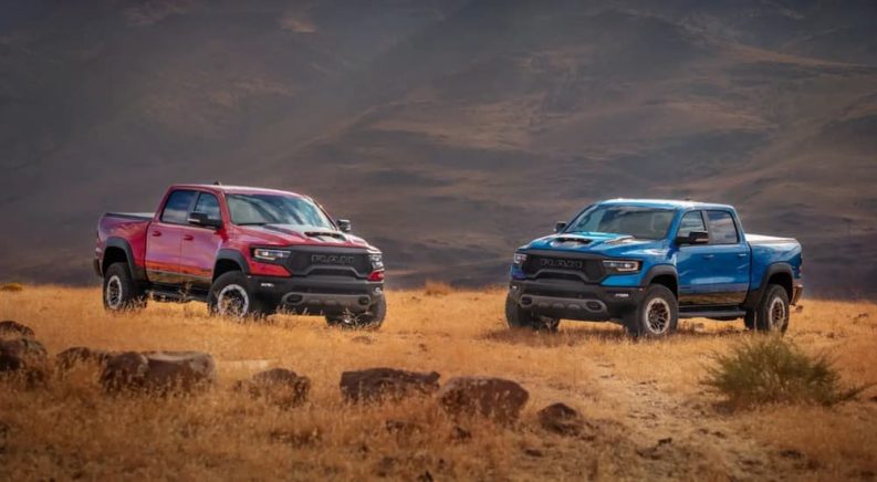 A red and a blue 2022 Ram 1500 TRX are shown facing each other in a field.