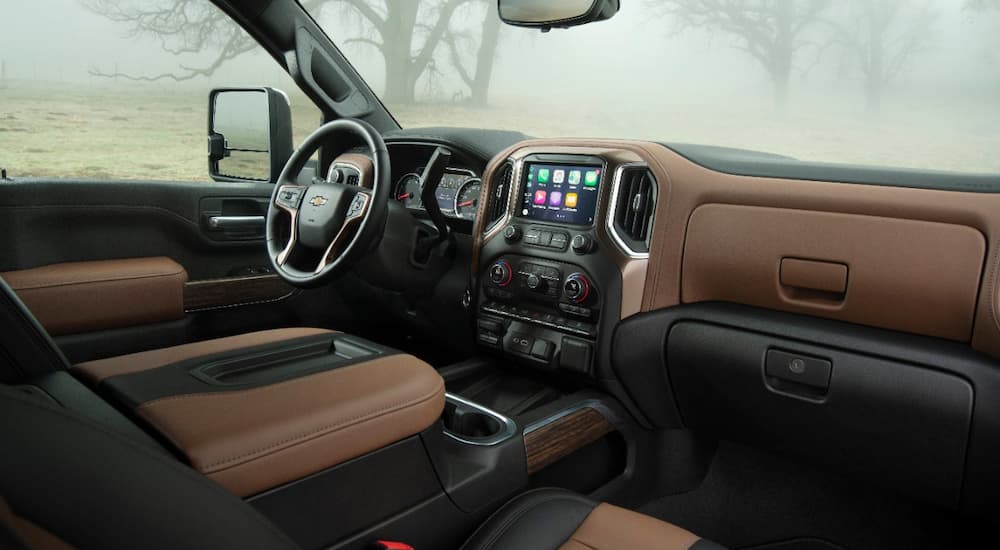 The black and brown interior of a 2022 Chevy Silverado 3500HD shows the steering wheel and center console.