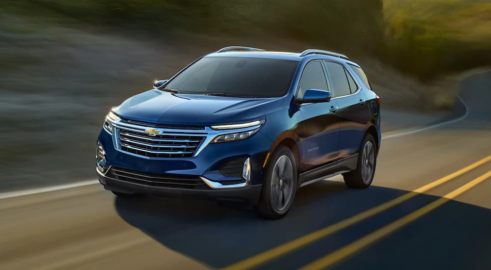 A blue 2022 Chevy Equinox is shown from the front driving on an open road after leaving a Chevy dealer.