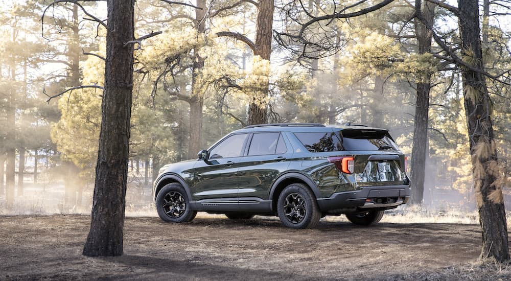 A dark green 2022 Ford Explorer Timberline is shown from a rear angle parked in the woods after leaving a local Ford dealer.