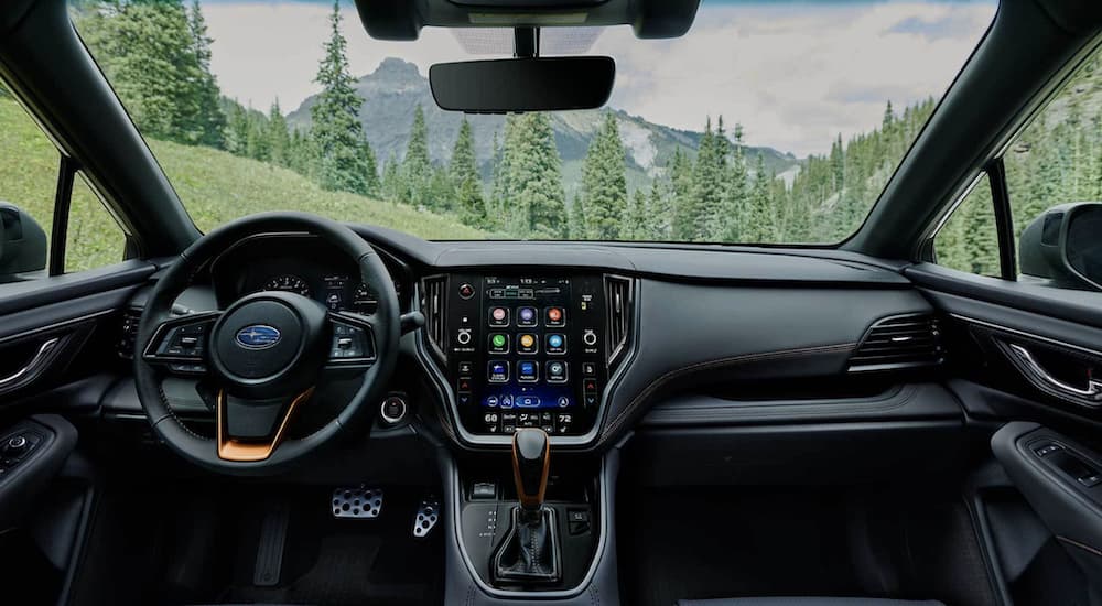 The black interior of a 2022 Subaru Outback Wilderness shows the steering wheel and infotainment screen.