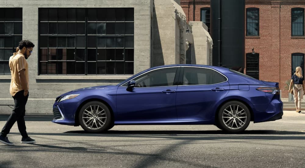 A blue 2022 Toyota Camry XLE is shown from the side parked in front of a building.