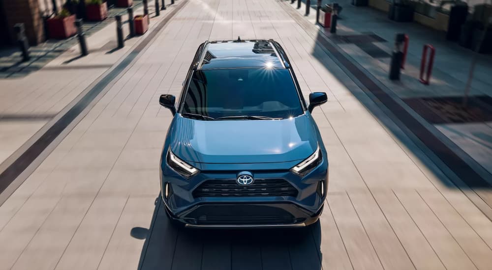 A blue 2022 Toyota RAV4 Hybrid XSE is shown from the front driving through a city after leaving a Toyota dealer.