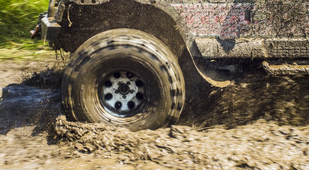 A vehicle is shown off-roading through a muddy puddle.