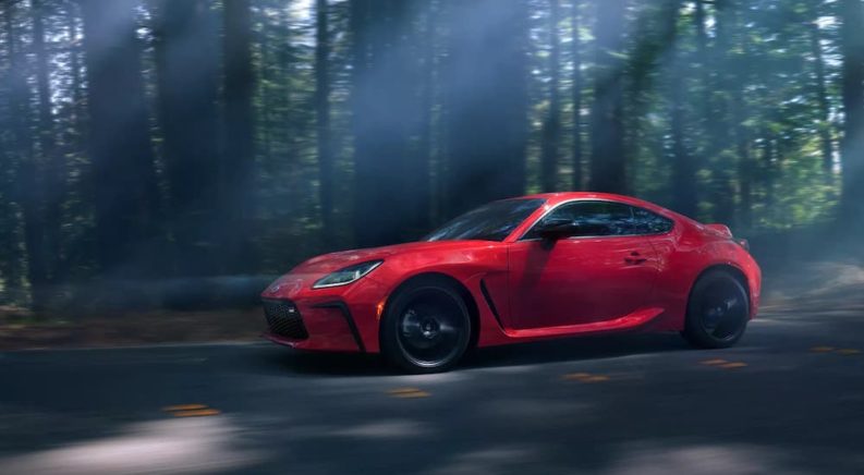 A red 2022 Toyota GR86 is shown from the side while speeding through the forest.