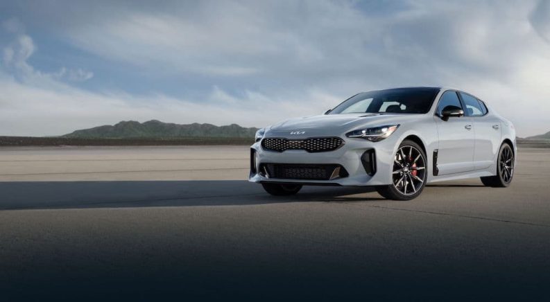A grey 2022 Kia Stinger is shown from the front while parked in front of mountains after leaving a Kia dealer in Sherwood Park.